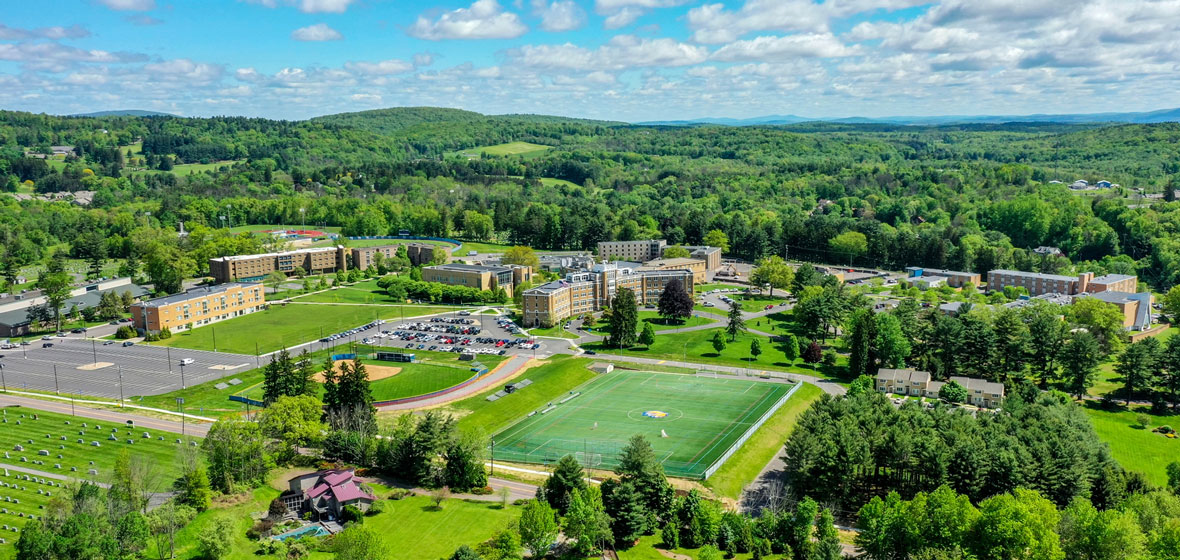 aerial view of the campus green lush woods in the background