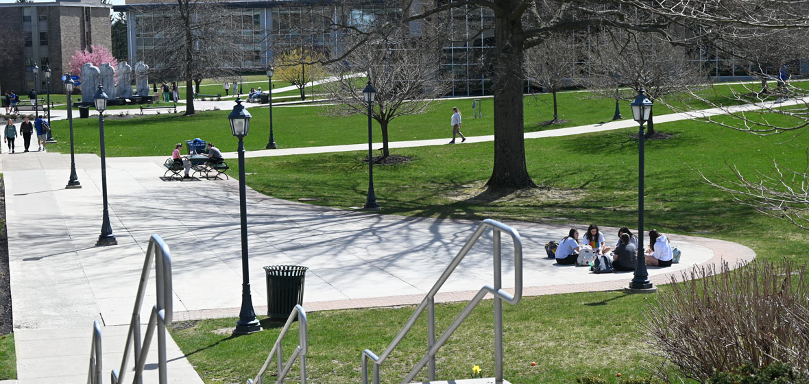 Students sitting on the lawn on campus by Henry Science Center building
