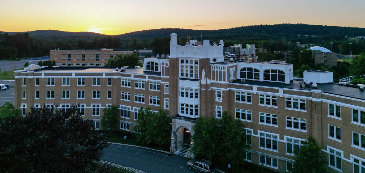 campus building with a bakcround of sunset behind green rolling hills